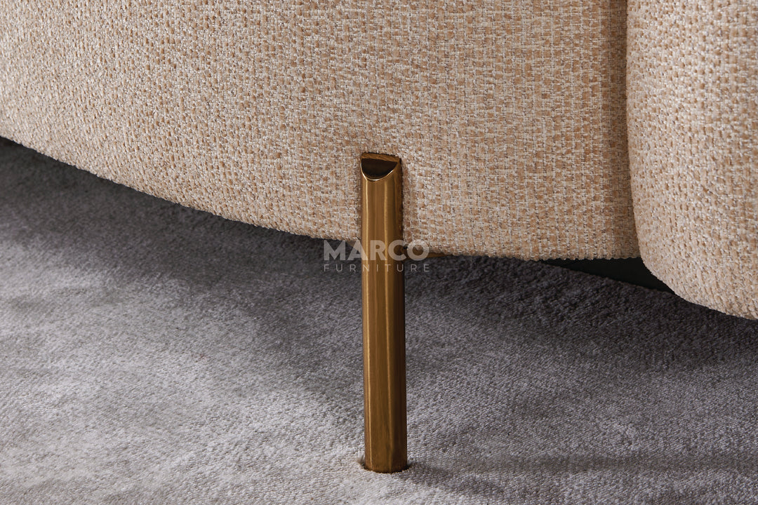 Close-up of a textured beige sofa leg on a gray carpet with 'MARCO' branding.