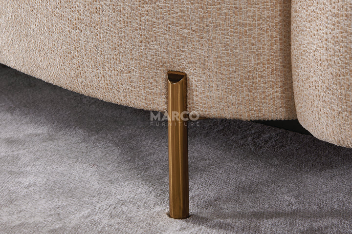 Close-up of a textured beige sofa leg on a gray carpet with 'MARCO' branding.