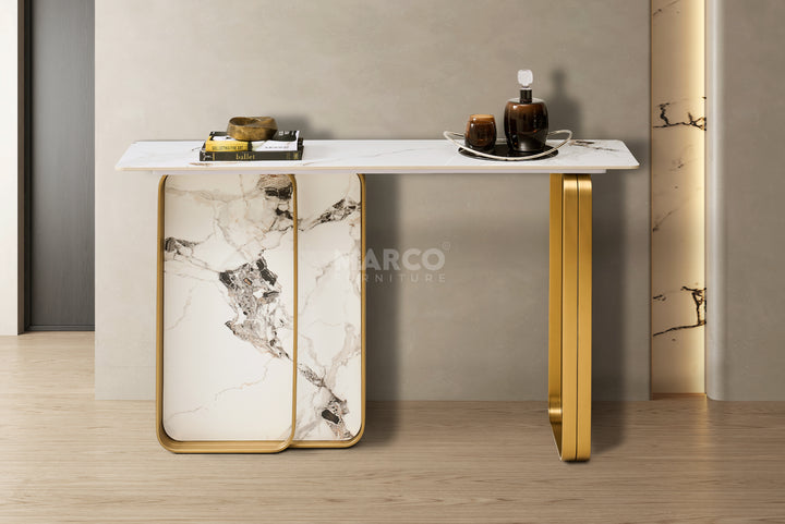 Modern console table with marble design and gold legs against a neutral wall.