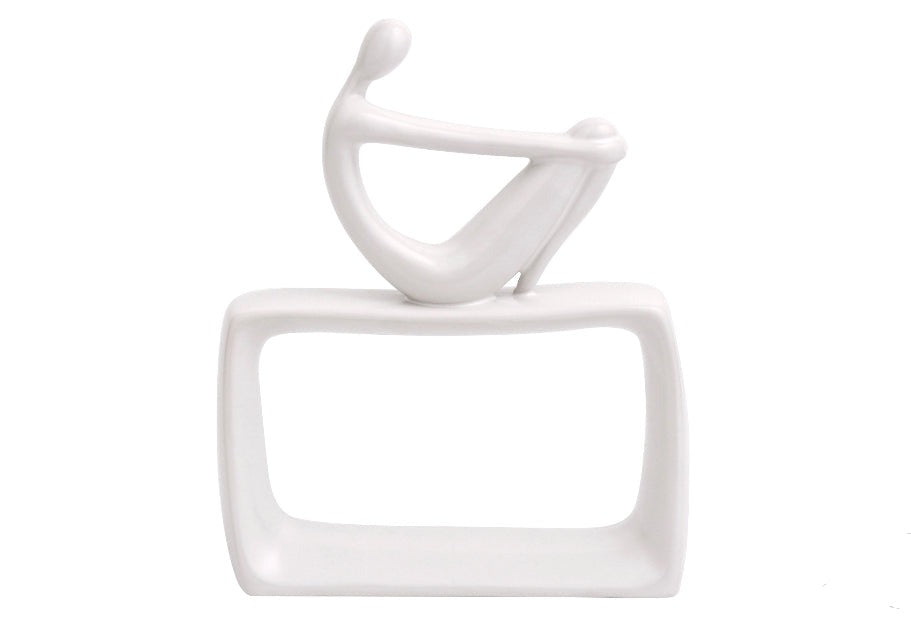White ceramic abstract sculpture of a seated figure with an abstract background.