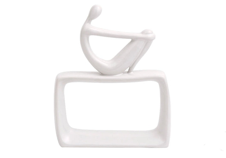 White ceramic abstract sculpture of a seated figure with an abstract background.