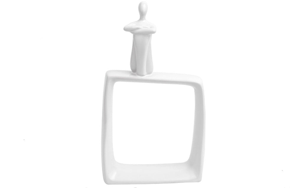 White ceramic sculpture of an abstract human figure sitting alone on a hollow rectangular base.