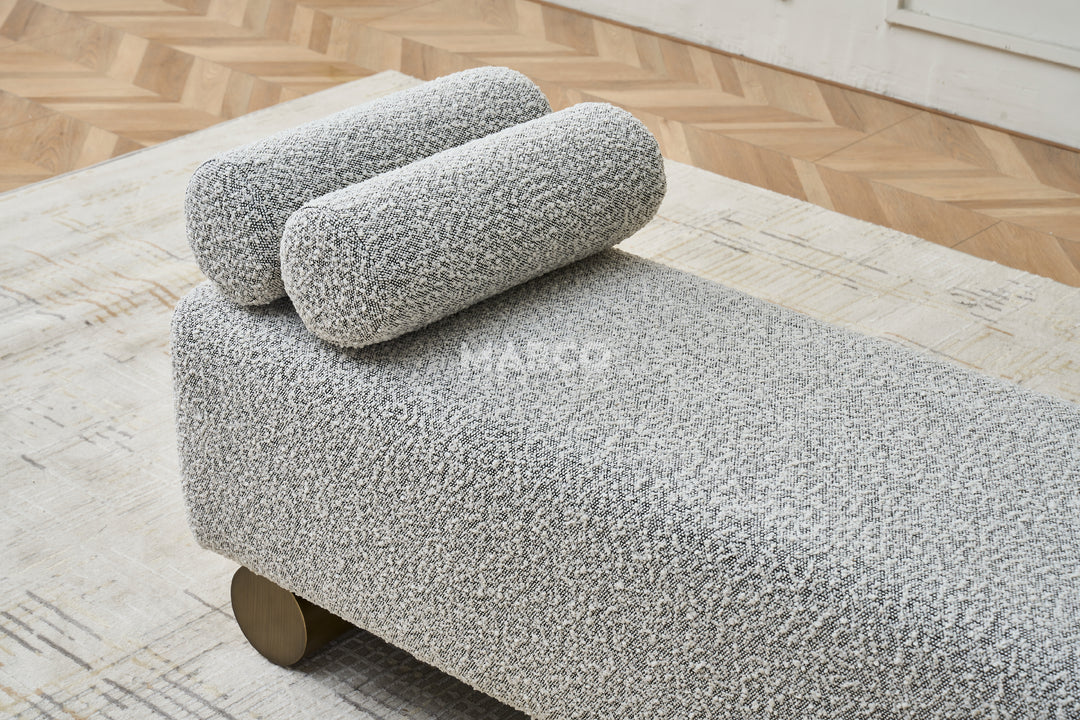 Gray textured ottoman with wooden legs in a modern living room setting.