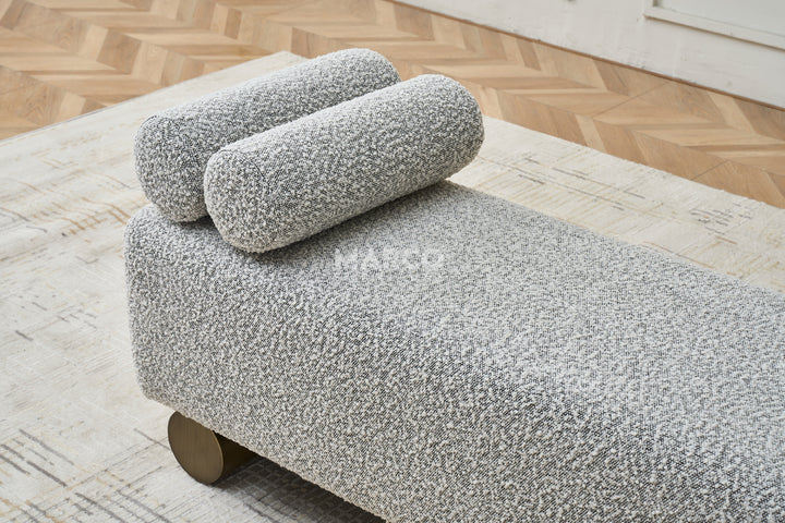 Gray textured ottoman with wooden legs in a modern living room setting.