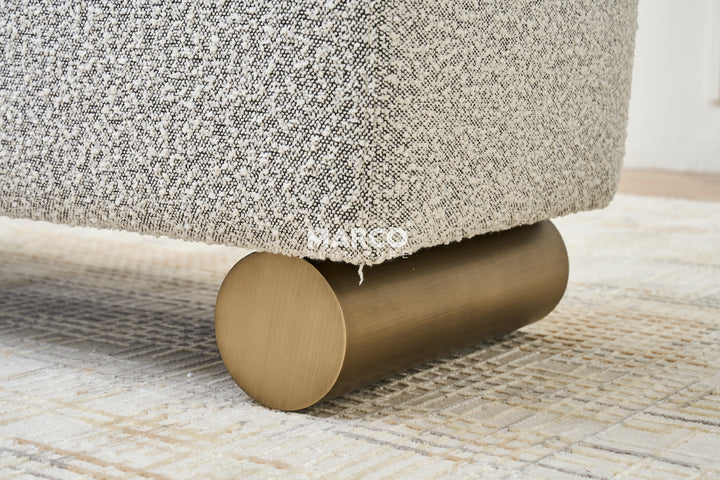 Gray textured ottoman with wooden legs in a modern living room setting.