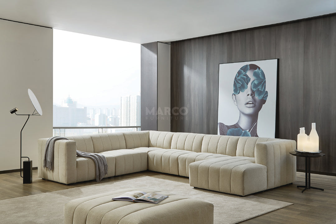 Modern living room with a beige sectional sofa, ottoman, and artwork on the wall.