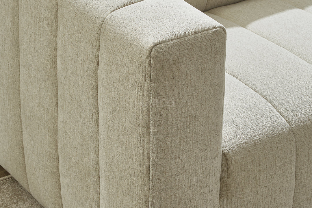 Close-up of a light green fabric sofa with a brand logo.