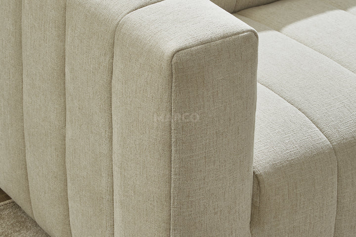 Close-up of a light green fabric sofa with a brand logo.