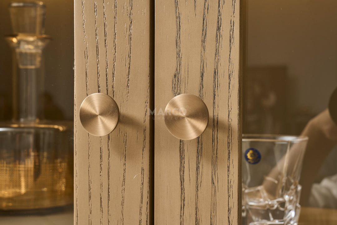 Close-up of a wooden cabinet with brass handles in a blurred interior setting