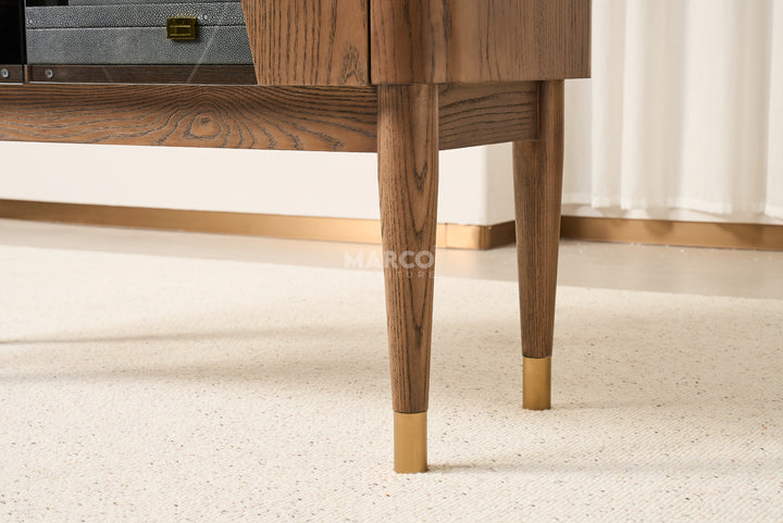 Wooden cabinet with gold feet on a light carpet