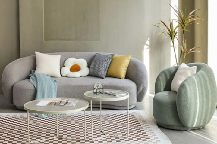 Modern living room with gray sofa, green armchair, and coffee tables.