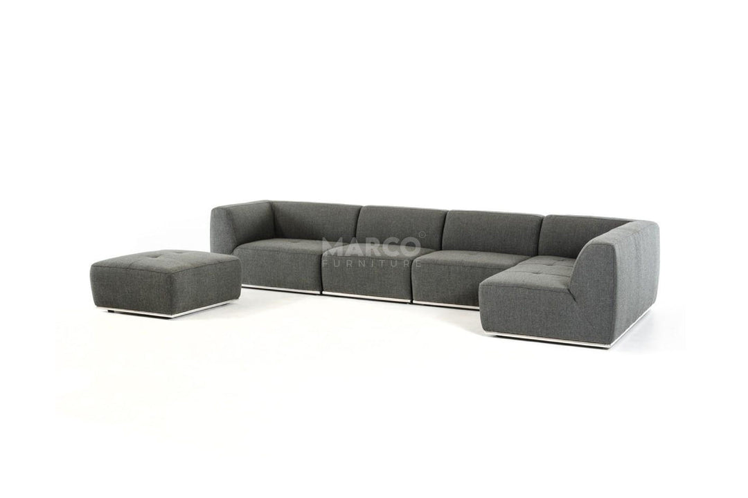 Gray sectional sofa with ottoman on a white background, featuring the brand 'Marco'.