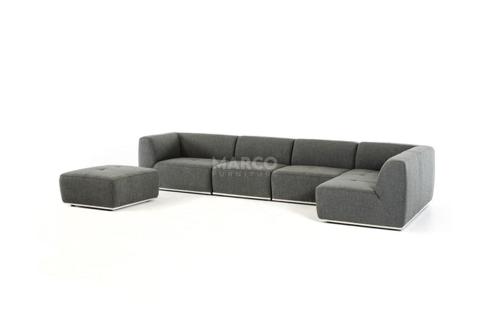 Gray sectional sofa with ottoman on a white background, featuring the brand 'Marco'.