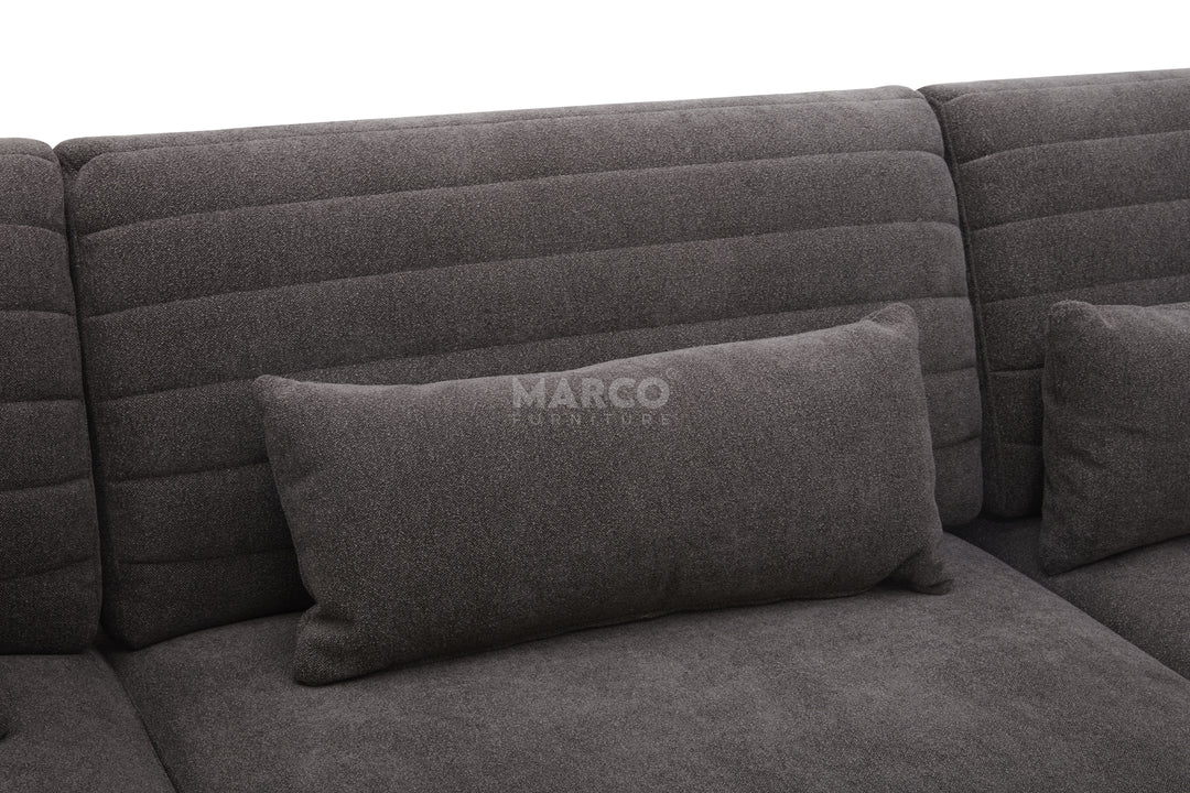 Gray sectional sofa with a pillow featuring the brand 'Marco' on a dark background