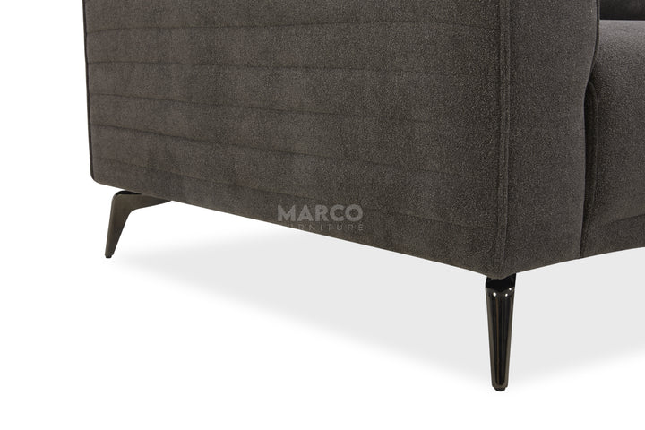 Gray upholstered chair with black legs on a white background, featuring the brand 'Marco'.