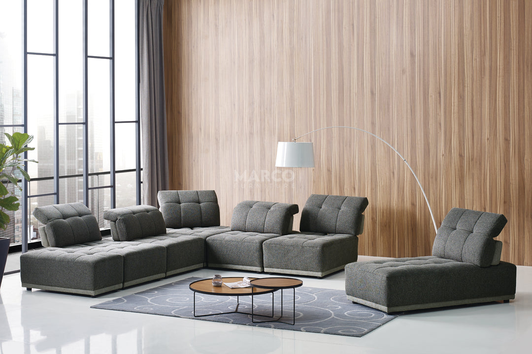 Modern gray sectional sofa in a room with large windows and wooden wall.