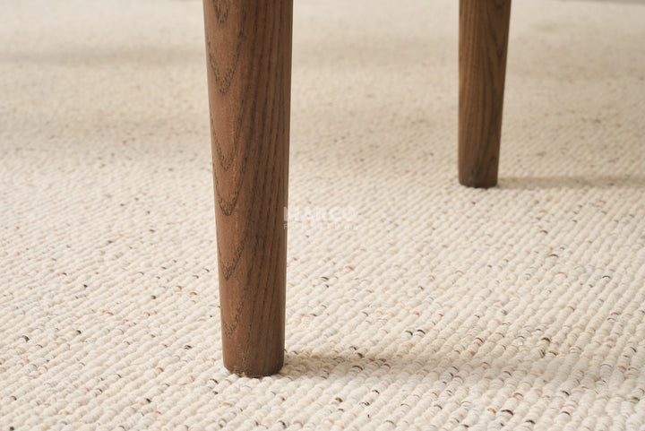Close-up of wooden legs on a textured beige carpet