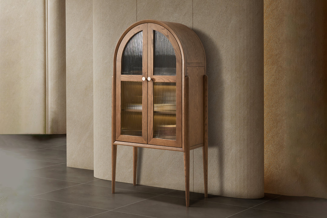 Wooden display cabinet with glass doors against a beige wall.