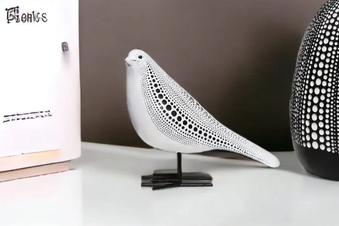 White ceramic bird sculpture on a black stand with a blurred background