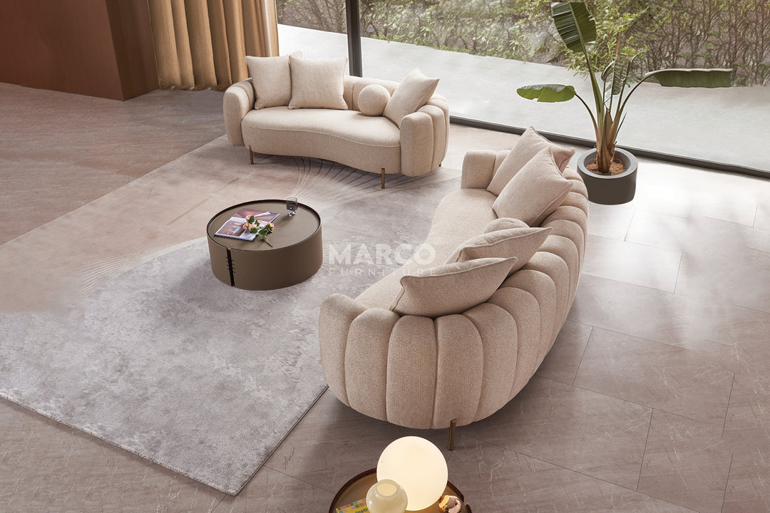 Modern living room with a curved beige sofa, coffee table, and decorative elements.