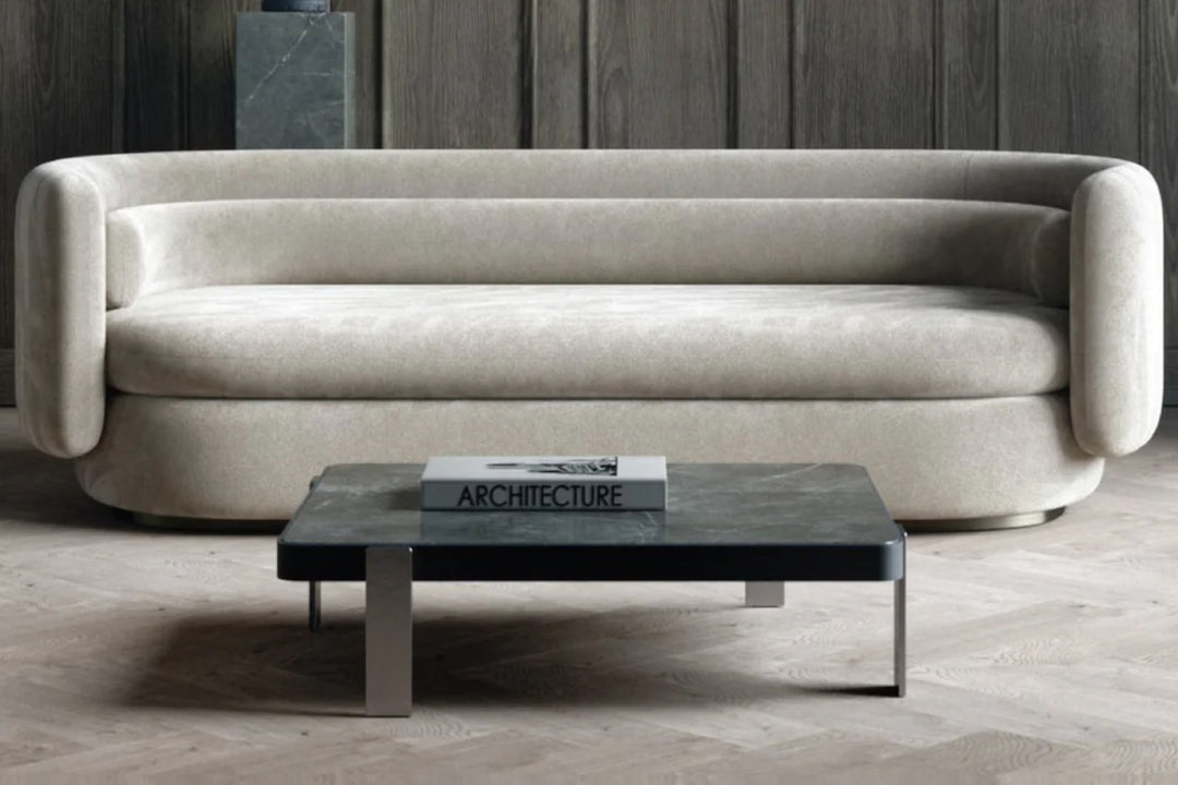 Beige sofa with a coffee table in a room with wooden flooring and a dark wall.
