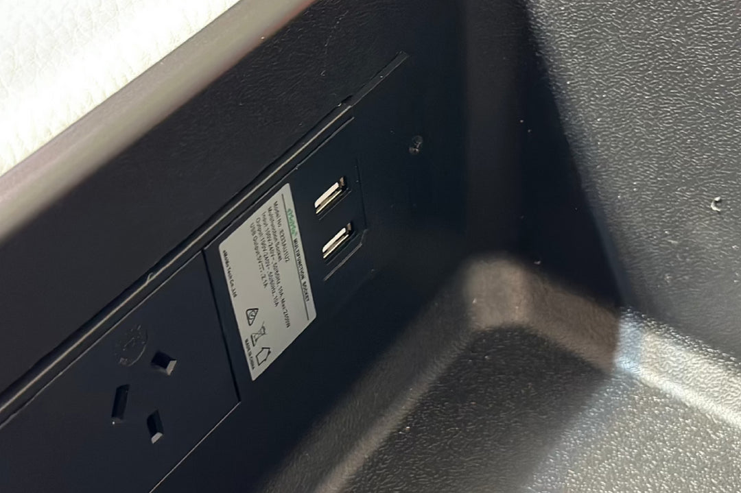 Close-up of a power outlet and USB ports on a black surface.