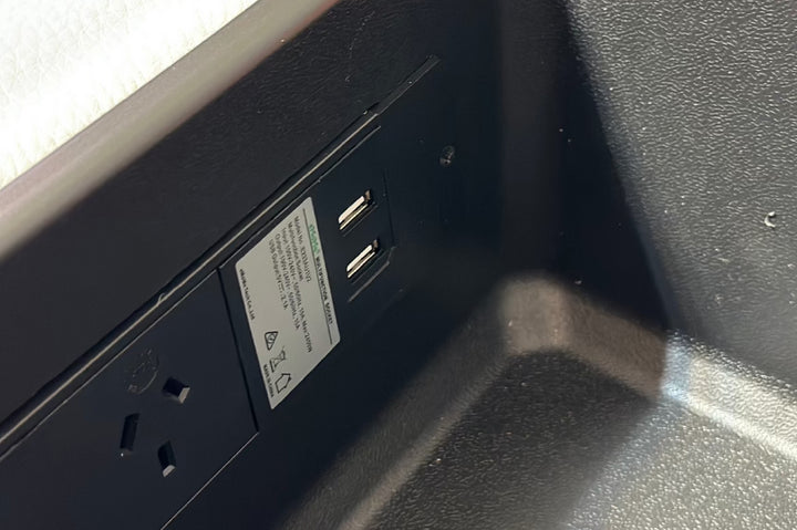 Close-up of a power outlet and USB ports on a black surface.