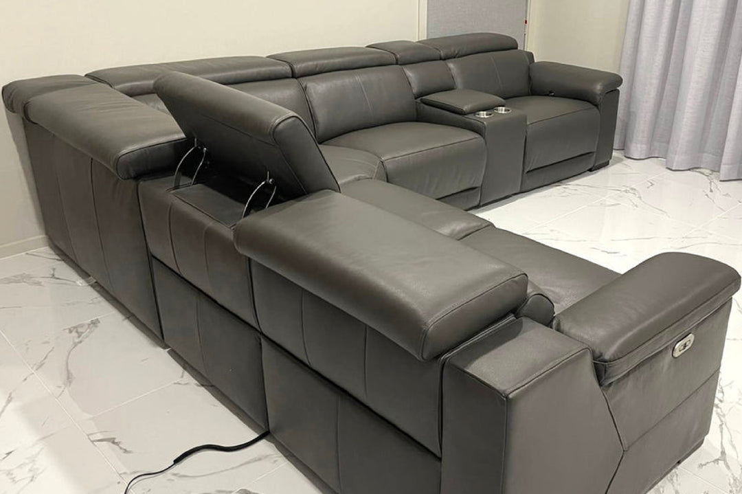 Gray sectional sofa with reclining seats on a marble floor.