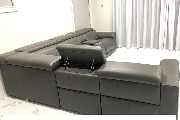 Gray sectional sofa with storage compartments in a room with white curtains.