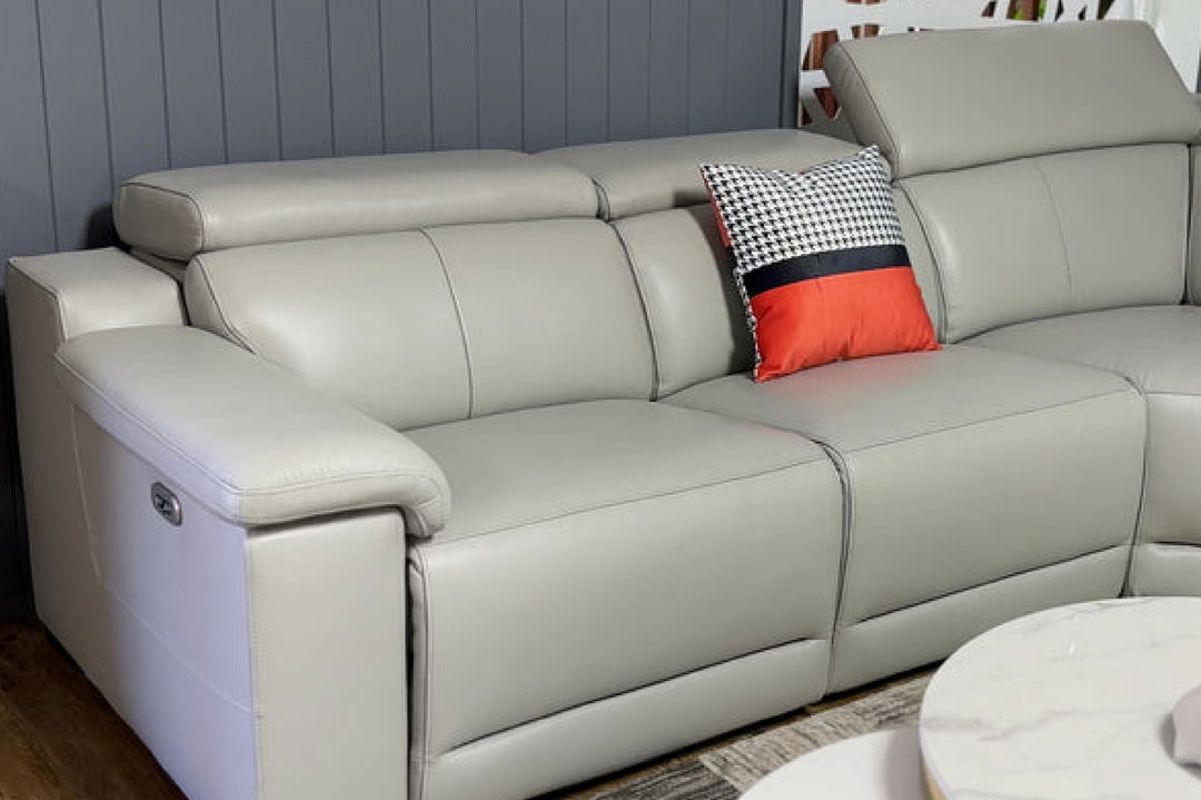Gray sectional sofa with a red and black patterned pillow against a gray wall.